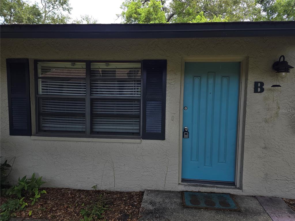 A light blue front door with a black lockbox sits beside a window with shutters — 447 6TH  NE AVENUE, LARGO, FL