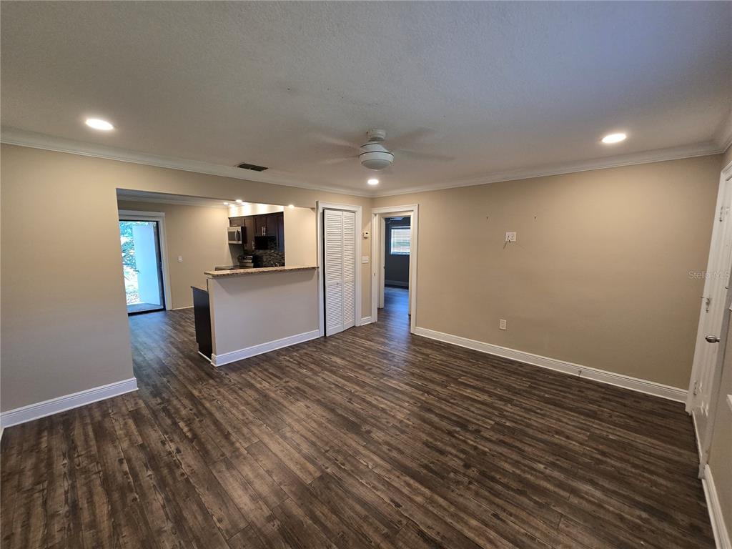 A living room with wood-look flooring, a ceiling fan, and an open kitchen pass-through — 447 6TH  NE AVENUE, LARGO, FL