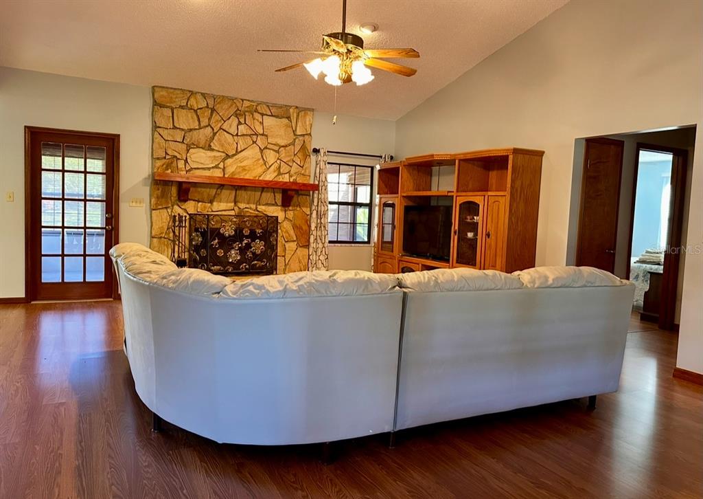 A living room features a stone fireplace, a large sectional sofa, and wood-look flooring — 5912 BAILEY ROAD, PLANT CITY, FL