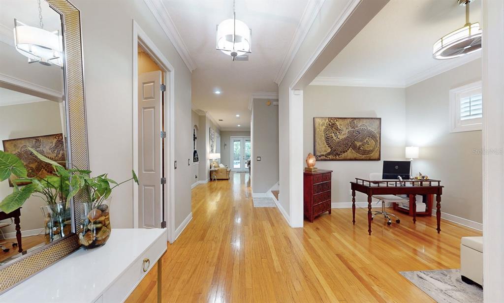 A bright hallway leads to a home office with hardwood floors and a dragon wall art — 116 S HESPERIDES STREET, TAMPA, FL