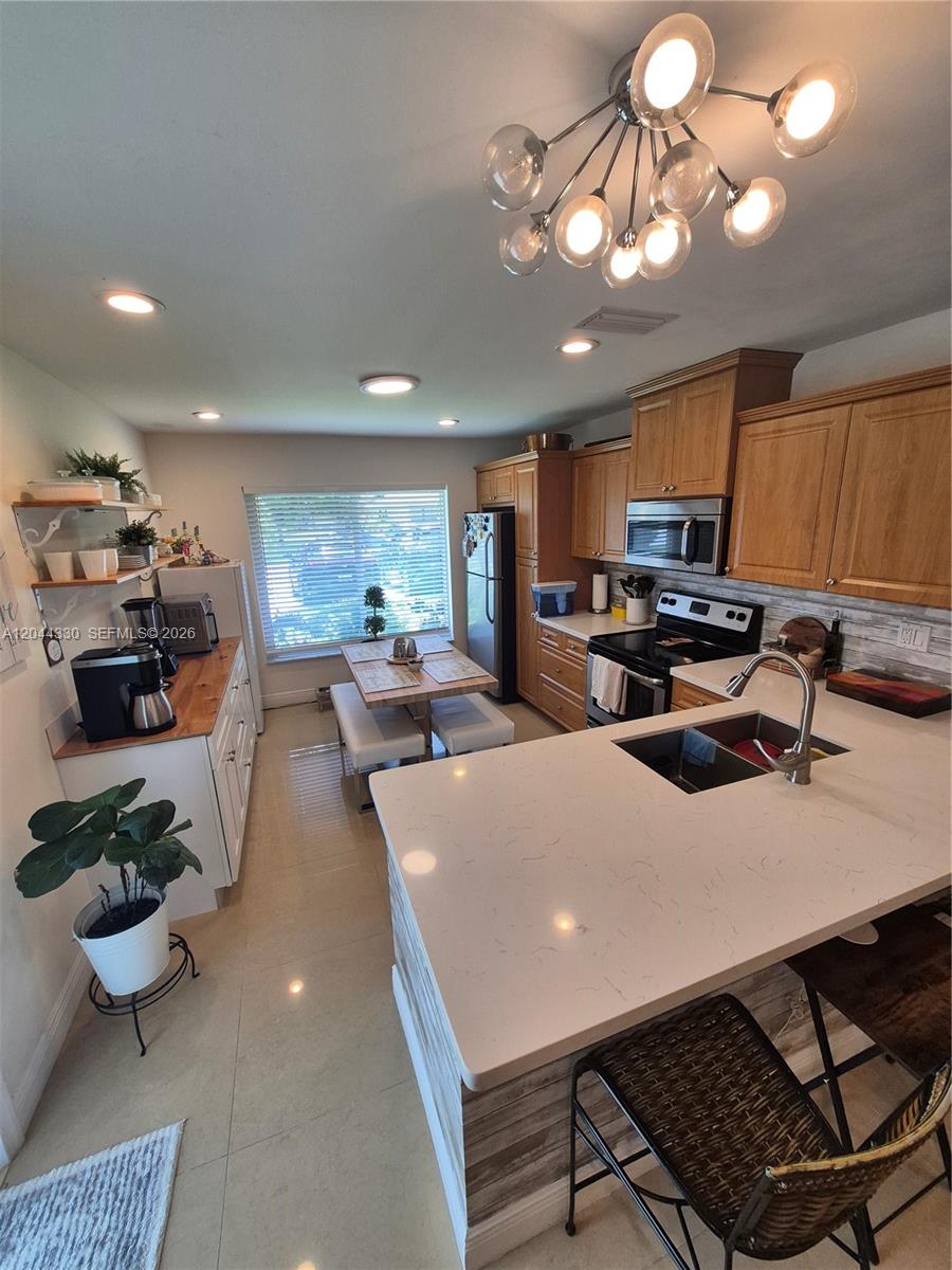 A kitchen features light wood cabinets, white countertops, a central island, and a dining area — 1359 Summit Run Cir, West Palm Beach FL 33415, WEST PALM BEACH, FL