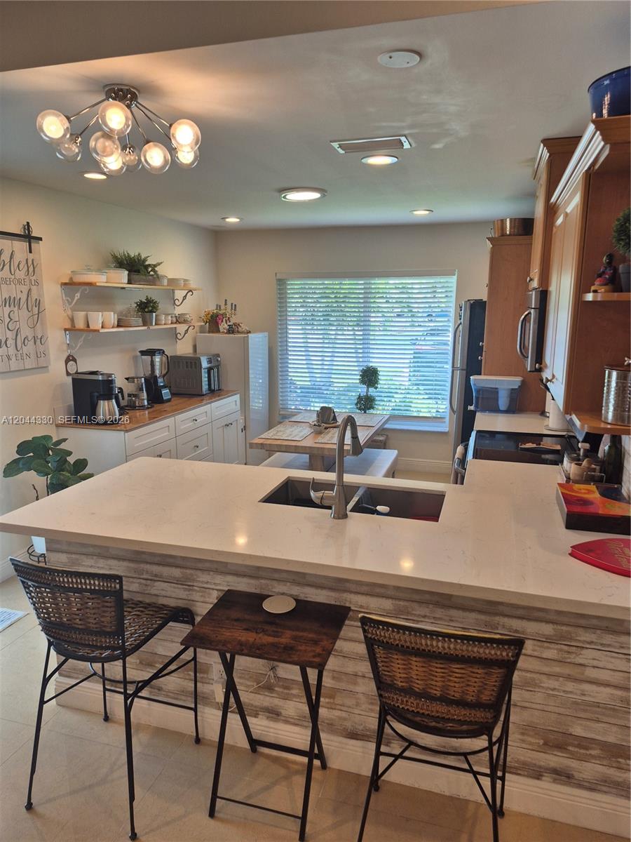 A kitchen features a white quartz peninsula, wood-look siding, and a dining area by a window — 1359 Summit Run Cir, West Palm Beach FL 33415, WEST PALM BEACH, FL