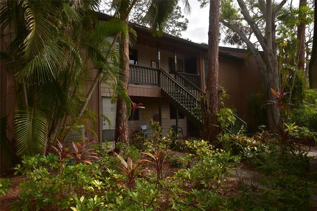 A two-story apartment building exterior features a wooden staircase leading to an upper balcony — 1608 BAYHOUSE POINT DRIVE UNIT GL304, SARASOTA, FL