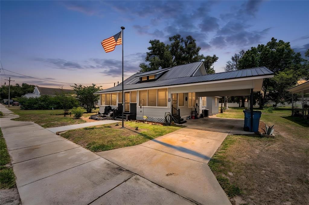 A single-story house with a metal roof, a carport, and an American flag in front — 113 SE PINE AVENUE, FORT MEADE, FL