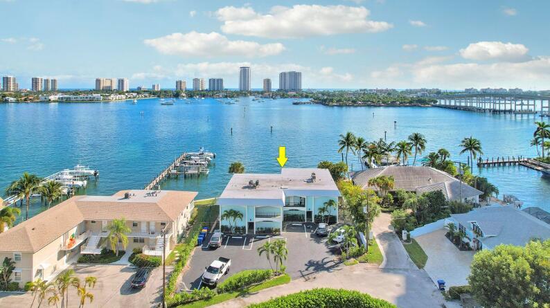 An aerial view shows a waterfront apartment building with a parking lot and boat docks — 360 Wilma Circle # 5, Riviera Beach FL 33404, RIVIERA BEACH, FL
