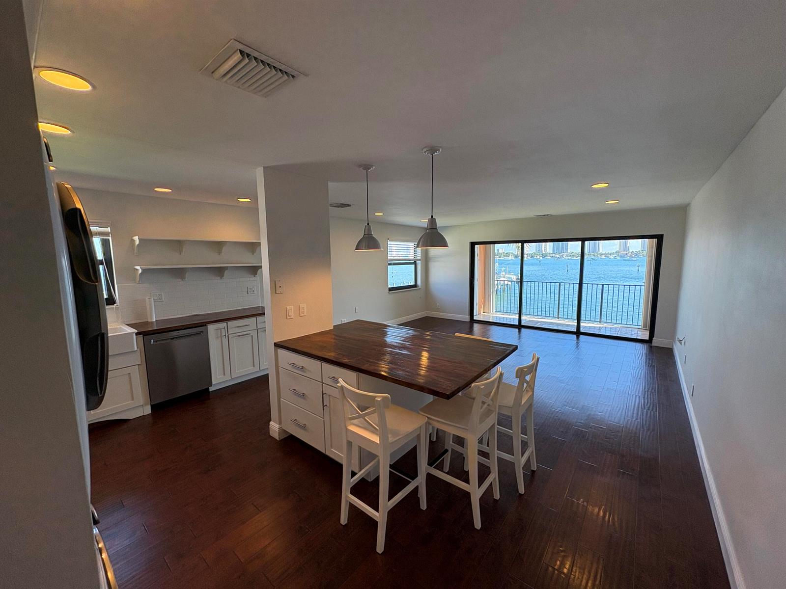A kitchen with a wooden island and white cabinets overlooks a balcony with water views — 360 Wilma Circle # 5, Riviera Beach FL 33404, RIVIERA BEACH, FL