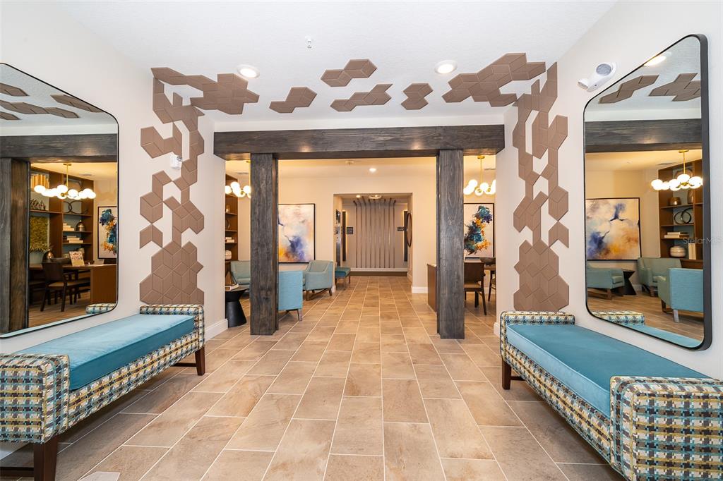 A lobby features two blue benches, large mirrors, and geometric wall accents around a doorway — 7521 LAUREATE BOULEVARD UNIT 5208, ORLANDO, FL
