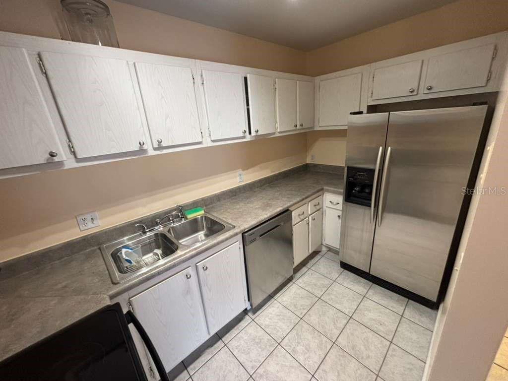 A kitchen with white cabinets, stainless steel appliances, a double sink, and tiled flooring — 660 62ND AVENUE N UNIT 1204, ST PETERSBURG, FL