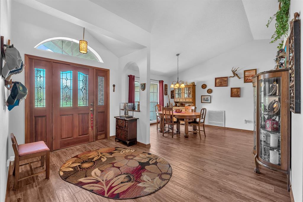 A foyer with a round floral rug leads into a dining area with wood flooring — 621 PENN NATIONAL ROAD, SEFFNER, FL
