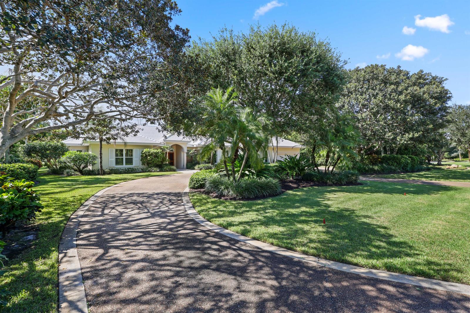 A curved driveway leads to a single-story house surrounded by lush trees and landscaping — 5 Country Road E # A, FL 33436, FL