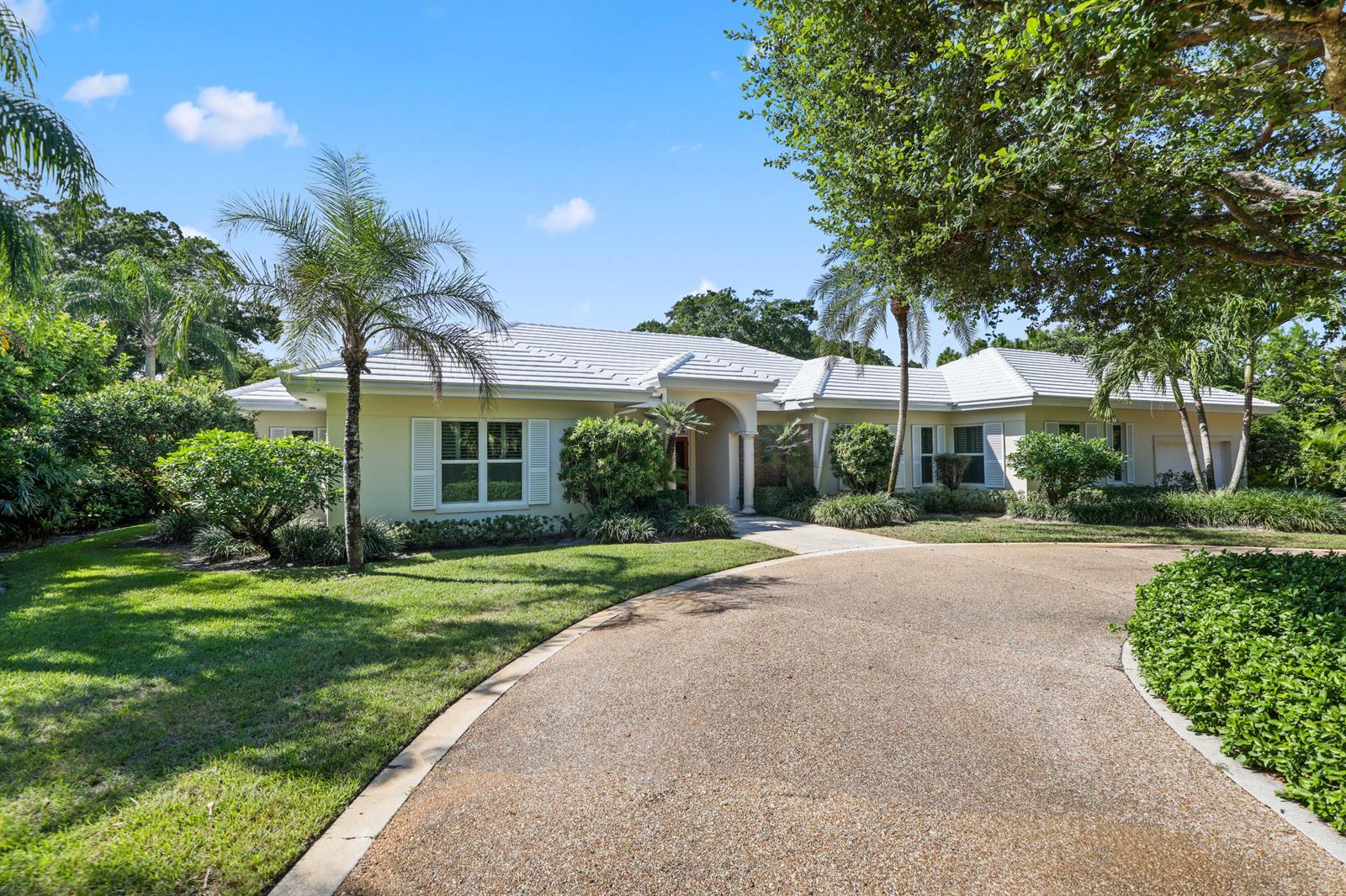 A single-story house with a white tile roof and a curved driveway sits among trees — 5 Country Road E # A, FL 33436, FL