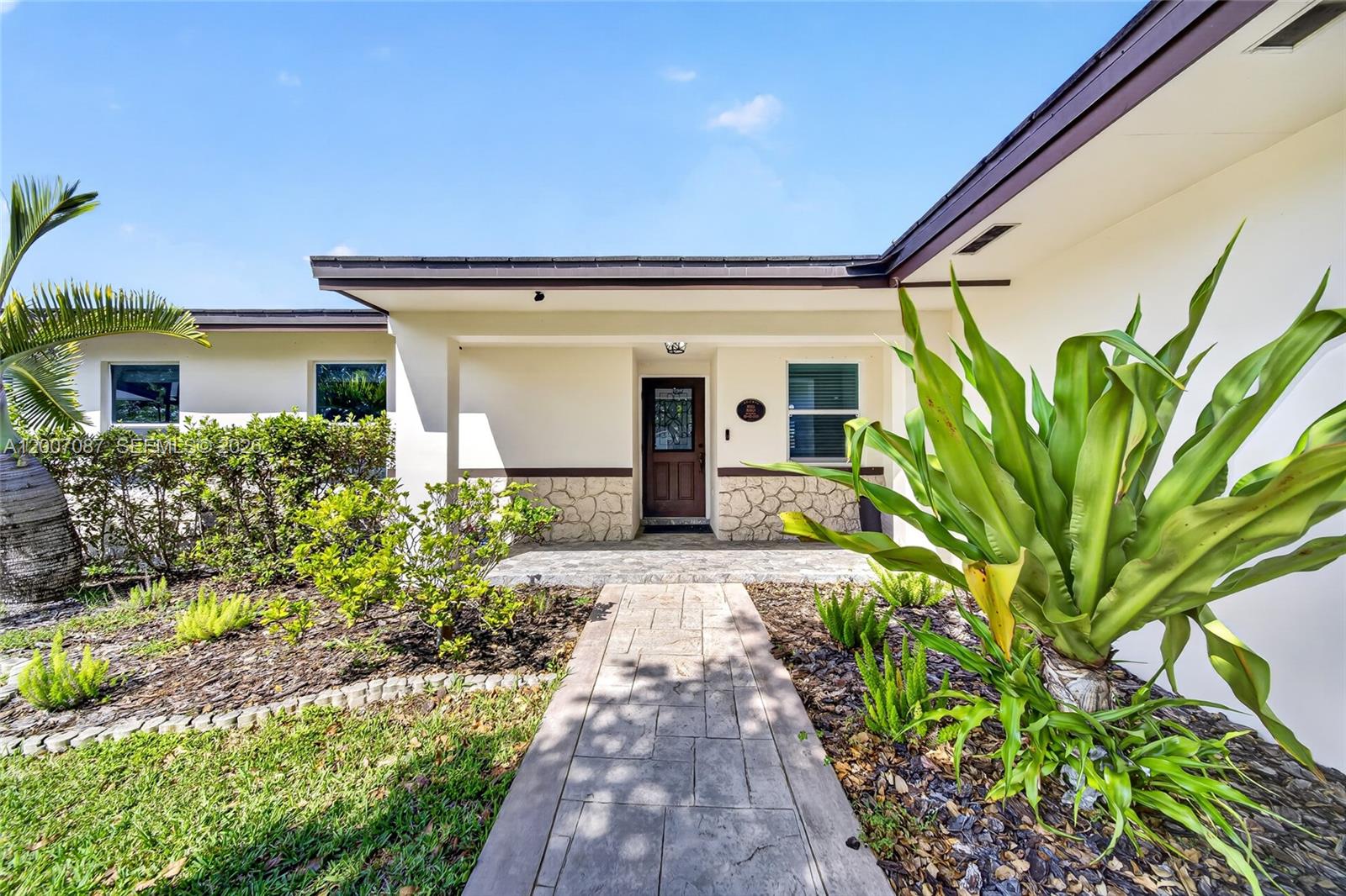 A stone-paved walkway leads to the front entrance of a house with stone accents — 7434 SW 129th Ct, Miami FL 33183, MIAMI, FL