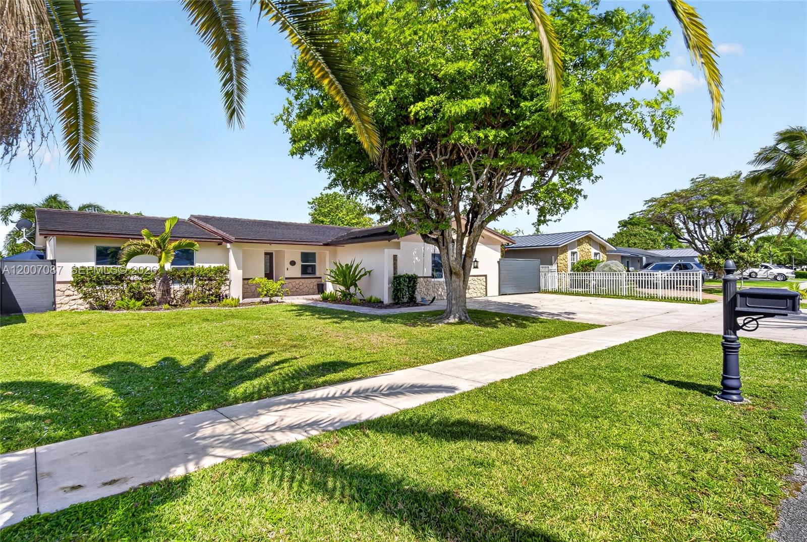A single-story house with a stone facade, a large tree, and a concrete driveway — 7434 SW 129th Ct, Miami FL 33183, MIAMI, FL