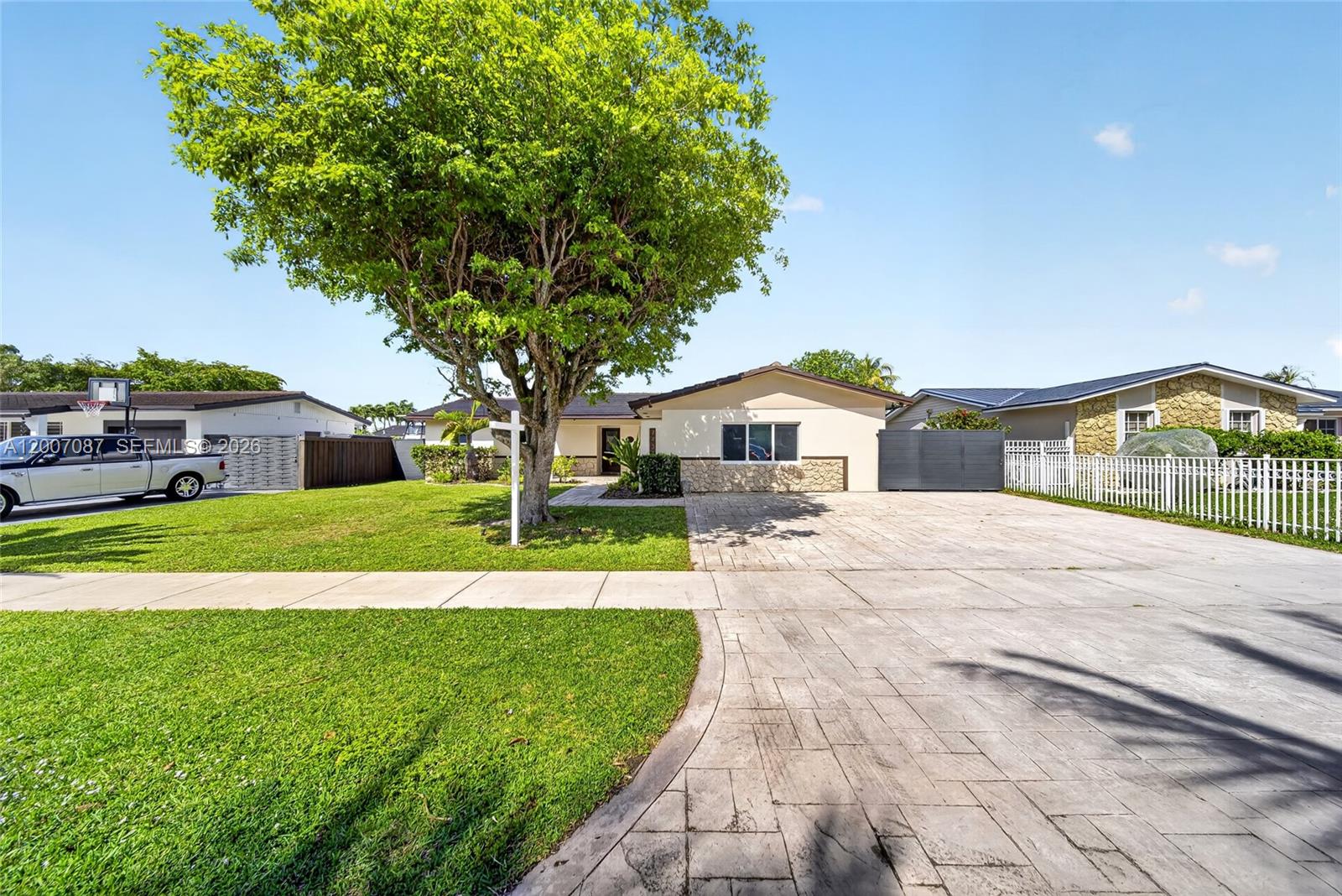 A single-story house with a paved driveway, a large tree, and a white fence — 7434 SW 129th Ct, Miami FL 33183, MIAMI, FL