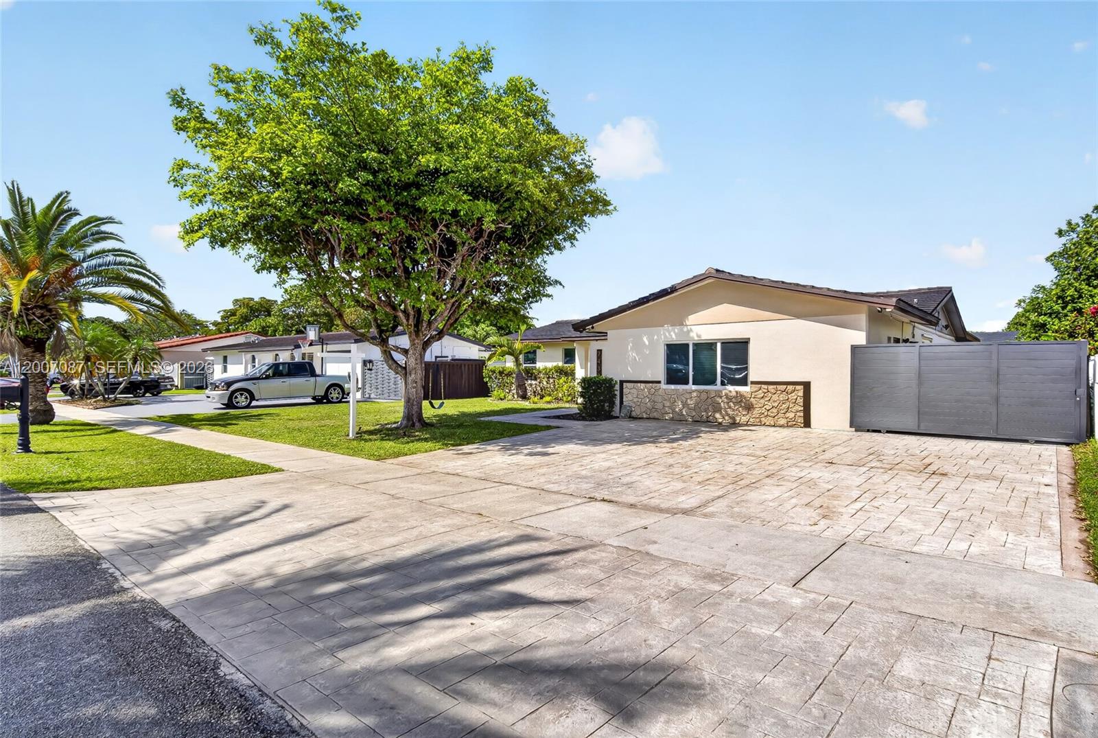 A single-story house with a paved driveway, stone accents, and a large tree in front — 7434 SW 129th Ct, Miami FL 33183, MIAMI, FL
