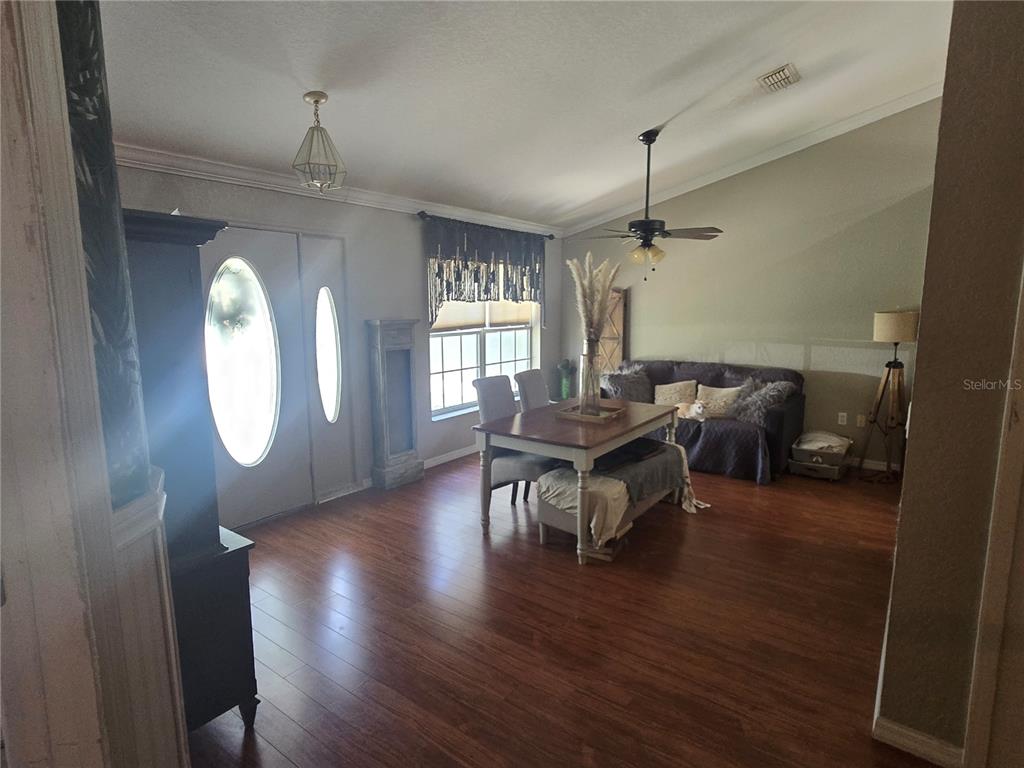 A dining area with wood flooring, a table, chairs, and a sofa near the entrance — 15444 MOUNT SPARROW ROAD, WEEKI WACHEE, FL