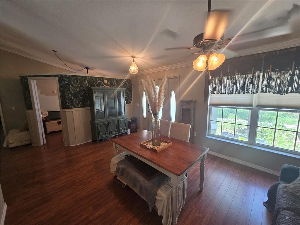 A dining area features a wooden table, upholstered chairs, and a sofa against a wall — 15444 MOUNT SPARROW ROAD, WEEKI WACHEE, FL