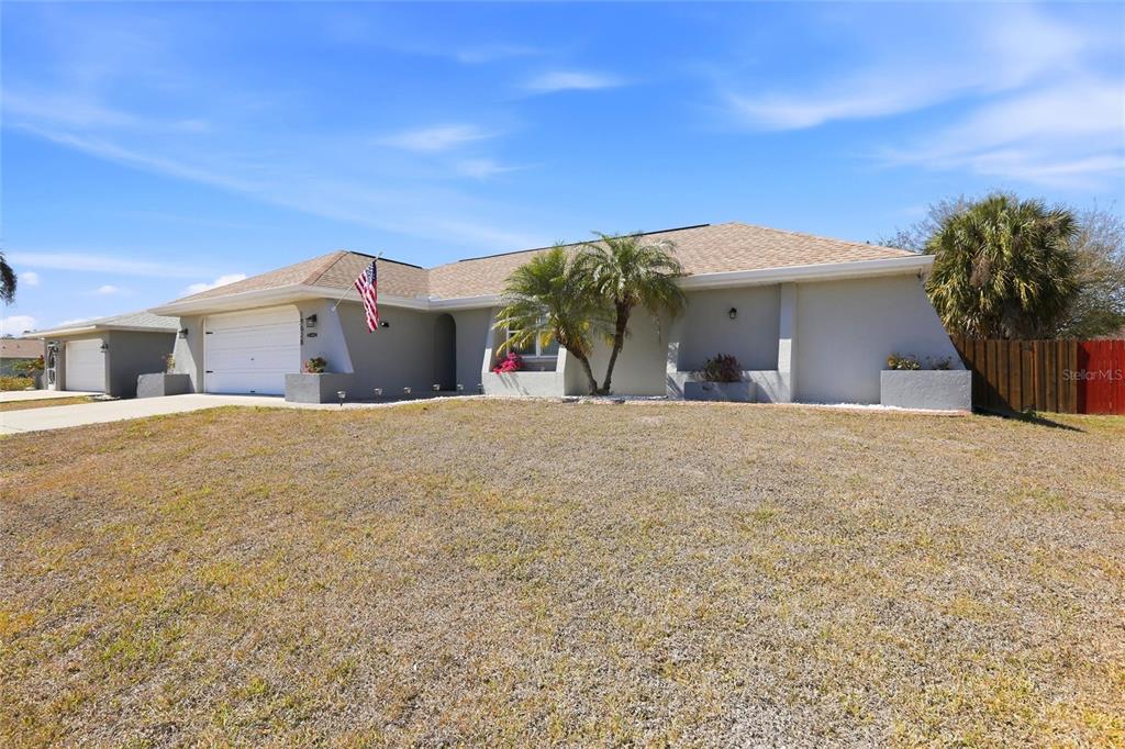 A single-story house with a gray exterior, a two-car garage, and a palm tree — 19628 MIDWAY BOULEVARD, PORT CHARLOTTE, FL