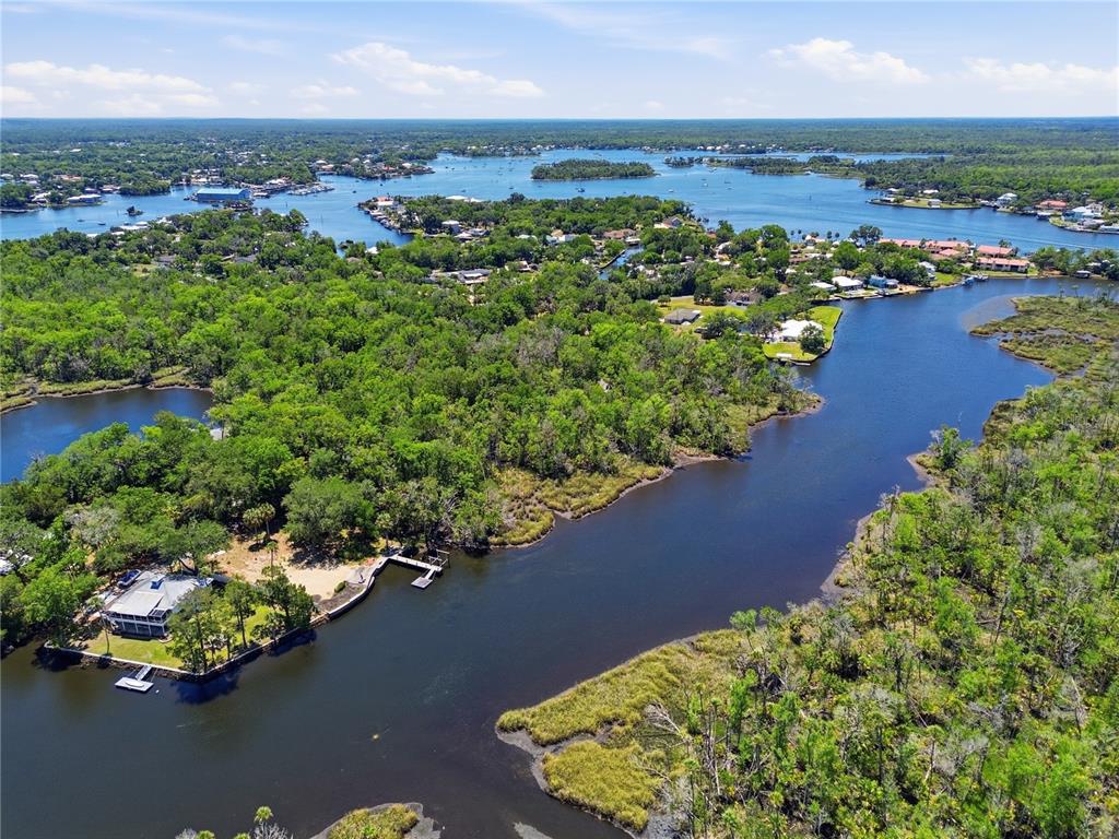 An aerial view shows a waterfront house surrounded by dense trees and marshy waterways — 650 MILLER CREEK ROAD, CRYSTAL RIVER, FL