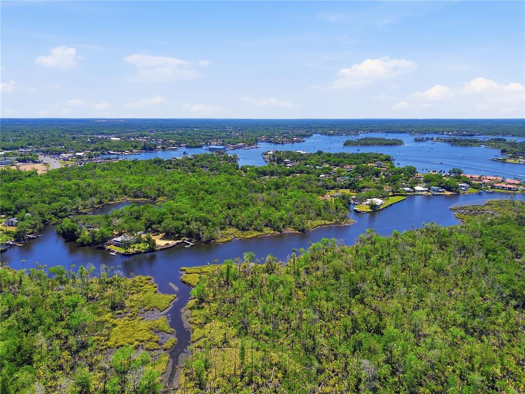 An aerial view shows a winding river flowing through a dense forest with scattered homes — 650 MILLER CREEK ROAD, CRYSTAL RIVER, FL