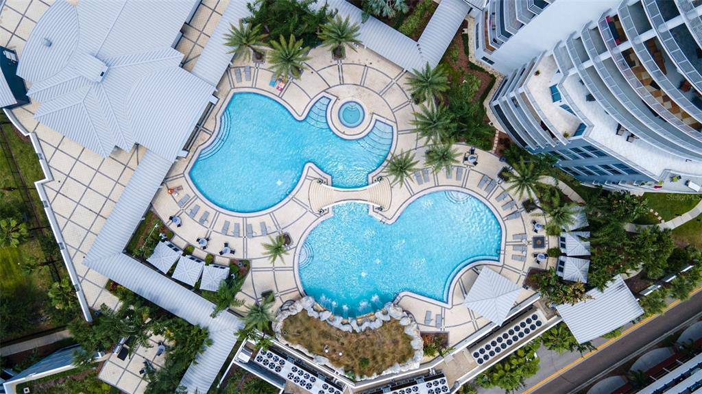 An aerial view shows a resort-style swimming pool complex with a bridge and rock feature — 1209 E CUMBERLAND AVENUE UNIT 2103, TAMPA, FL