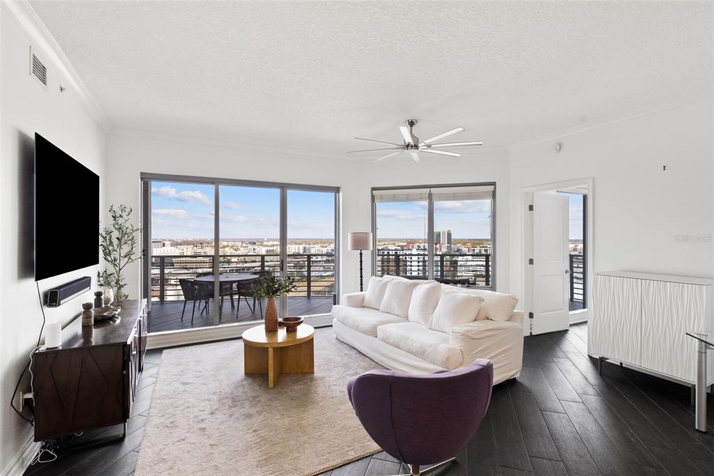 A modern living room with white walls, dark wood floors, a balcony, and city views — 1209 E CUMBERLAND AVENUE UNIT 2103, TAMPA, FL