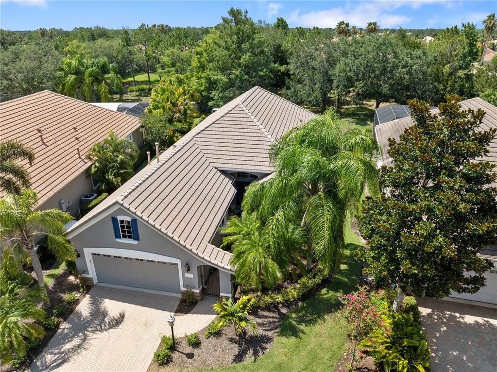 An aerial view shows a gray house with a tiled roof, garage, and surrounding landscaping — 7245 ORCHID ISLAND PLACE, LAKEWOOD RANCH, FL