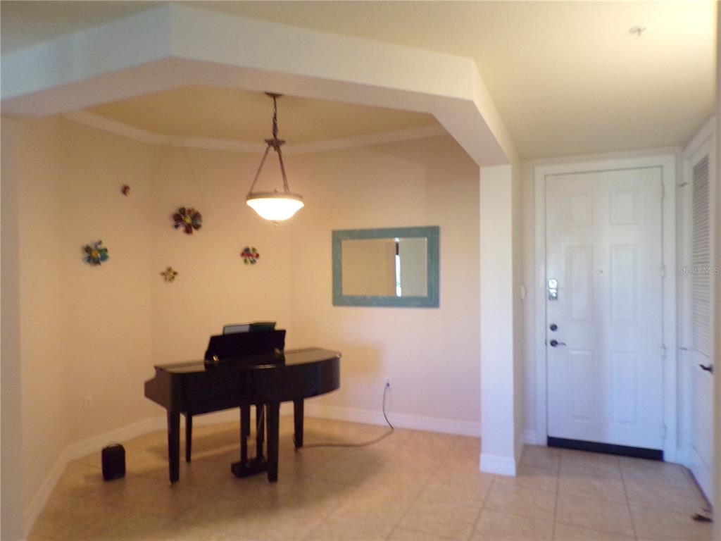A foyer area features a black grand piano, a pendant light, and tile flooring — 94 VIVANTE BOULEVARD UNIT 302/9432, PUNTA GORDA, FL