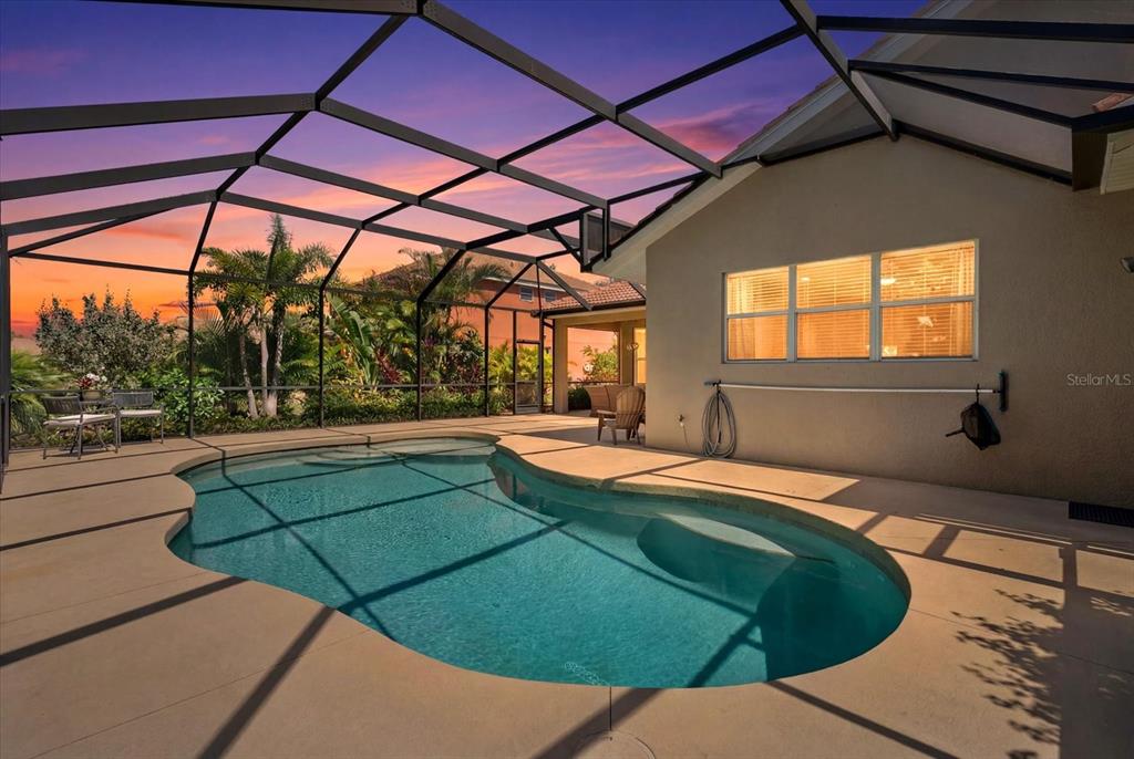 A screened-in patio features a kidney-shaped swimming pool and a view of the sunset — 9013 KINGSBURY PLACE, BRADENTON, FL