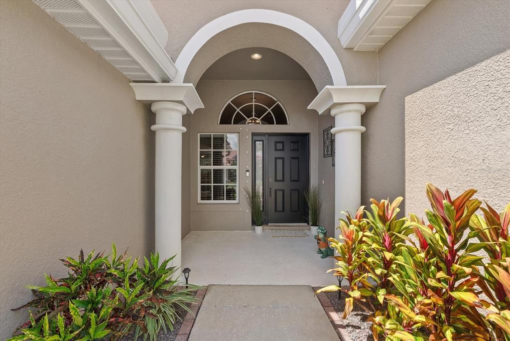 A covered entryway features a dark front door, arched architectural detail, and two white columns — 9013 KINGSBURY PLACE, BRADENTON, FL