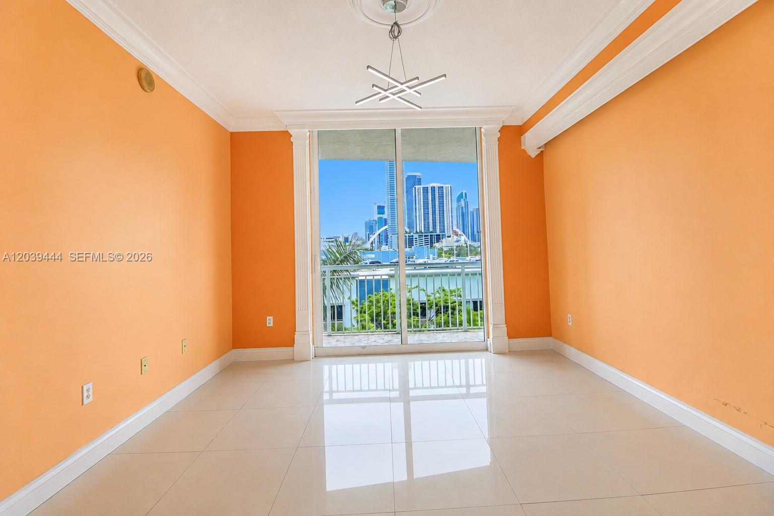 An empty room with orange walls, tile flooring, and a balcony overlooking city skyscrapers — 275 NE 18th St # 504, Miami FL 33132, MIAMI, FL