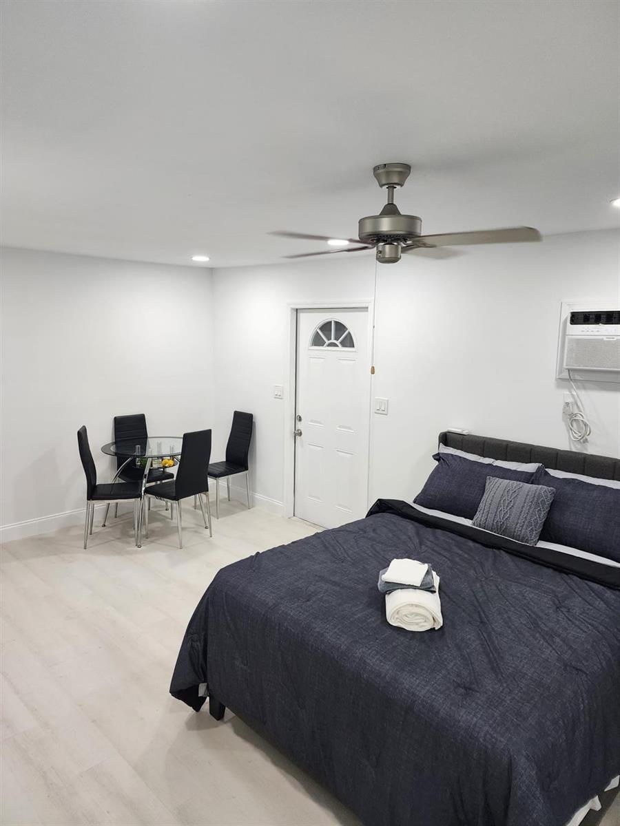 A bedroom features a bed with dark bedding, a small dining set, and a ceiling fan — 320 NW 4th Avenue # 4, Deerfield Beach FL 33441, DEERFIELD BEACH, FL