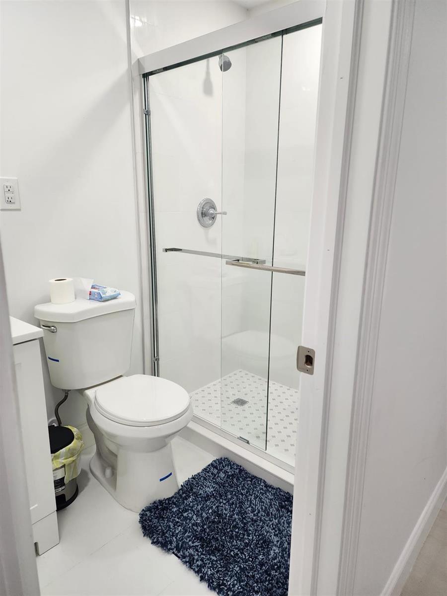 A small bathroom features a white toilet, a glass-enclosed shower, and a blue rug — 320 NW 4th Avenue # 4, Deerfield Beach FL 33441, DEERFIELD BEACH, FL