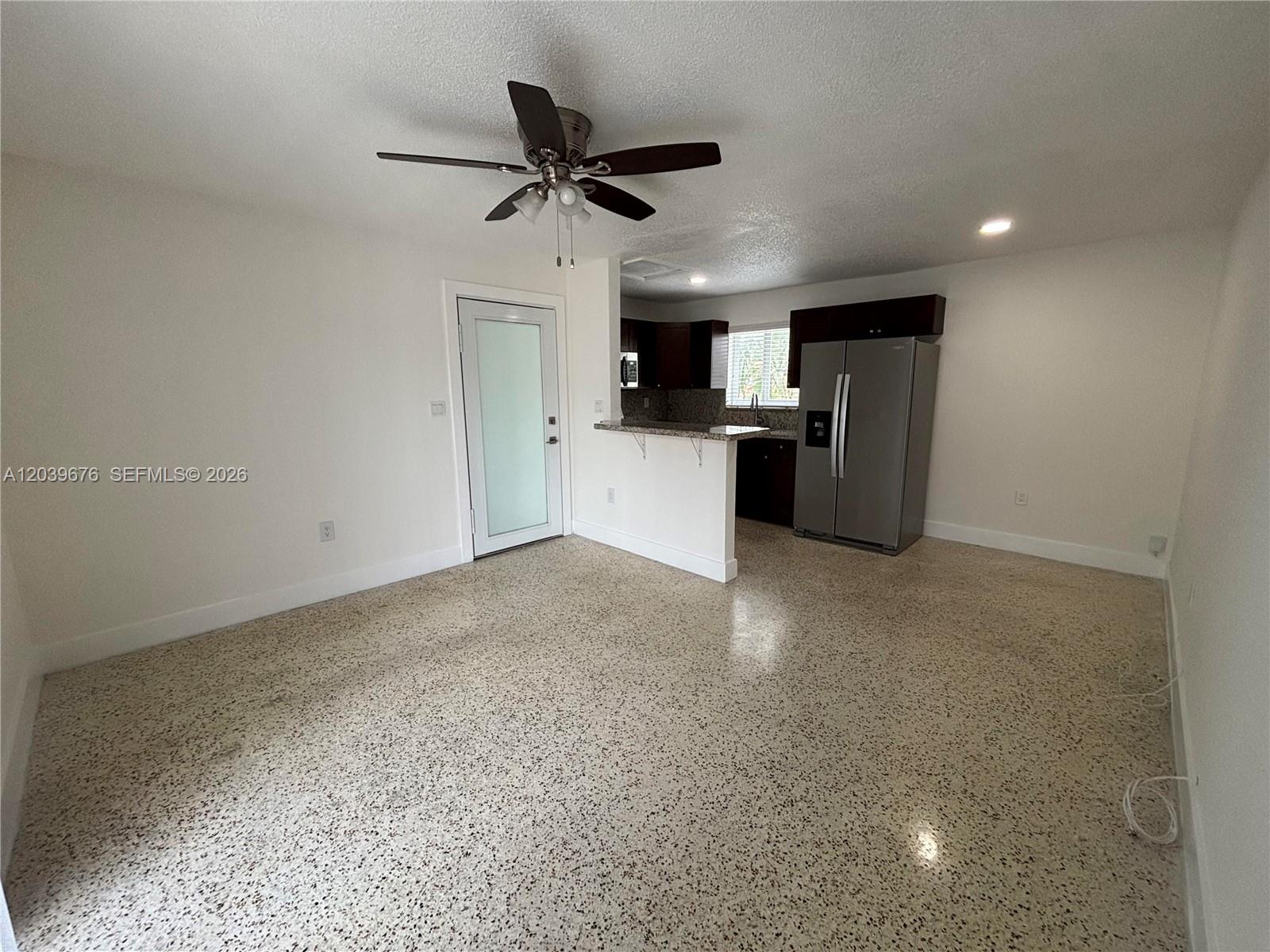 This room features a kitchen with dark cabinets, a stainless refrigerator, and speckled flooring — 458 E 31st St # 3, Hialeah FL 33013, HIALEAH, FL