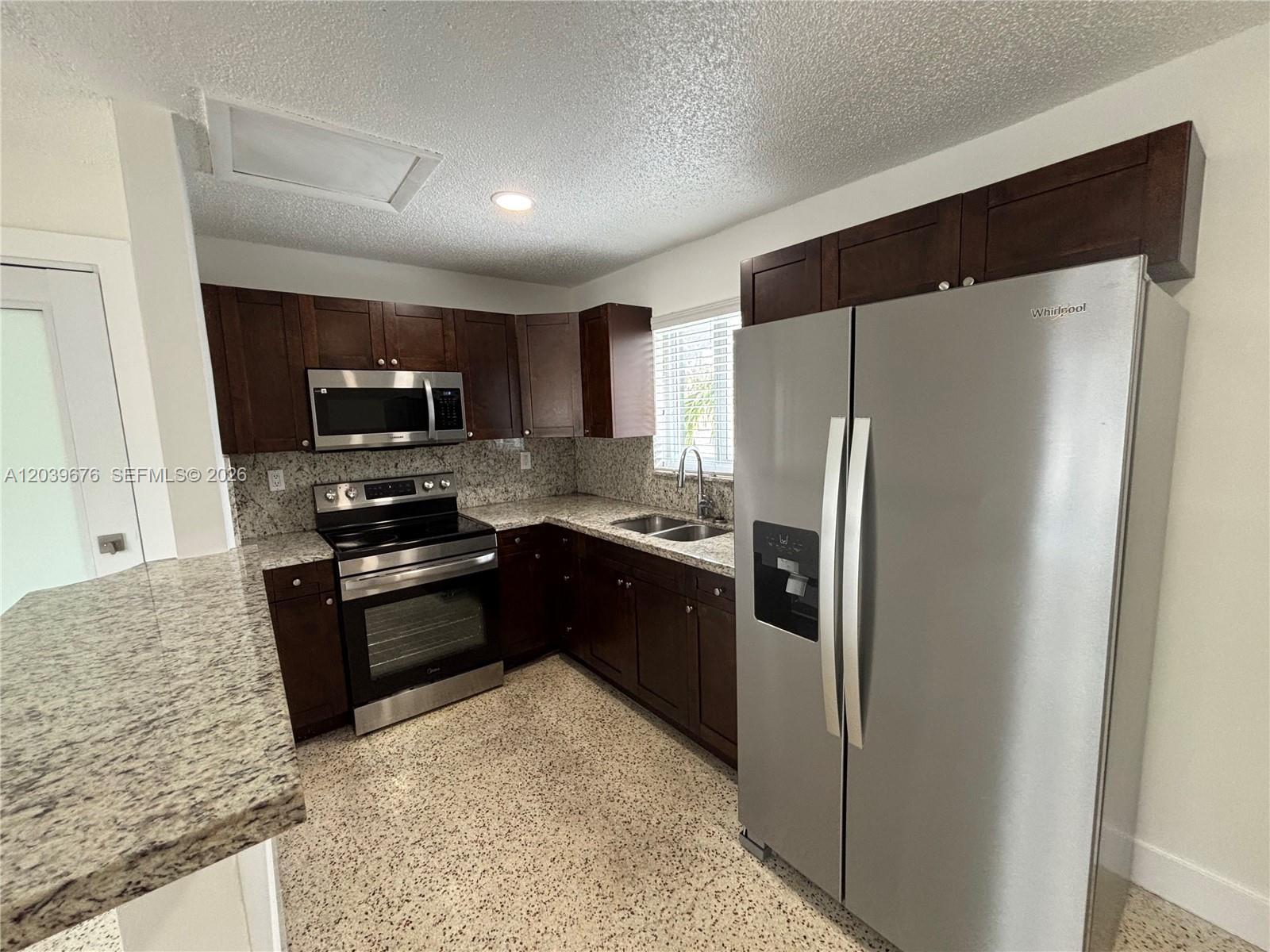 A kitchen features dark wood cabinets, stainless steel appliances, and speckled granite countertops — 458 E 31st St # 3, Hialeah FL 33013, HIALEAH, FL