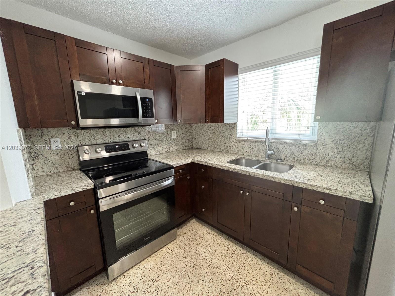A kitchen features dark wood cabinets, granite countertops, stainless steel appliances, and a double sink — 458 E 31st St # 3, Hialeah FL 33013, HIALEAH, FL