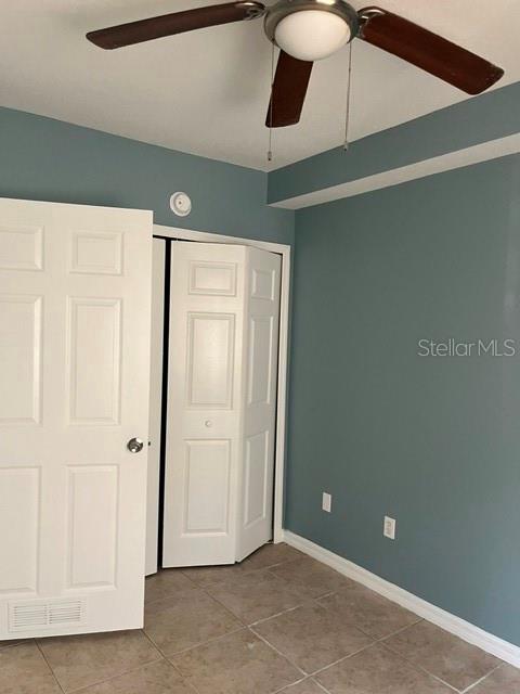 A room with blue walls, tile flooring, a ceiling fan, and white closet doors — 495 LAS CORTES LANE UNIT 102, ORLANDO, FL