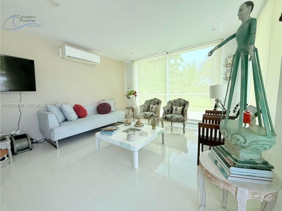 A living room features a light gray sofa, white coffee table, and a large sculpture — 1 Karibana Beach & Golf Condominium # 202, 00000, FL