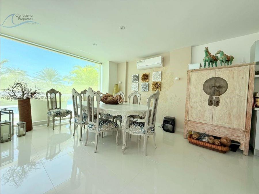 A dining room features a white table, patterned chairs, a large cabinet, and floor-to-ceiling windows — 1 Karibana Beach & Golf Condominium # 202, 00000, FL