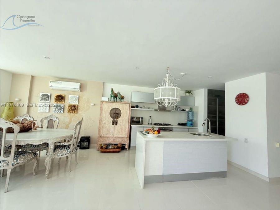 An open-concept kitchen and dining area features a white island, chandelier, and patterned chairs — 1 Karibana Beach & Golf Condominium # 202, 00000, FL