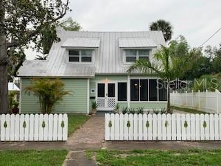 A light green two-story house with a metal roof and a white picket fence — 305 MARY AVENUE, NEW SMYRNA BEACH, FL