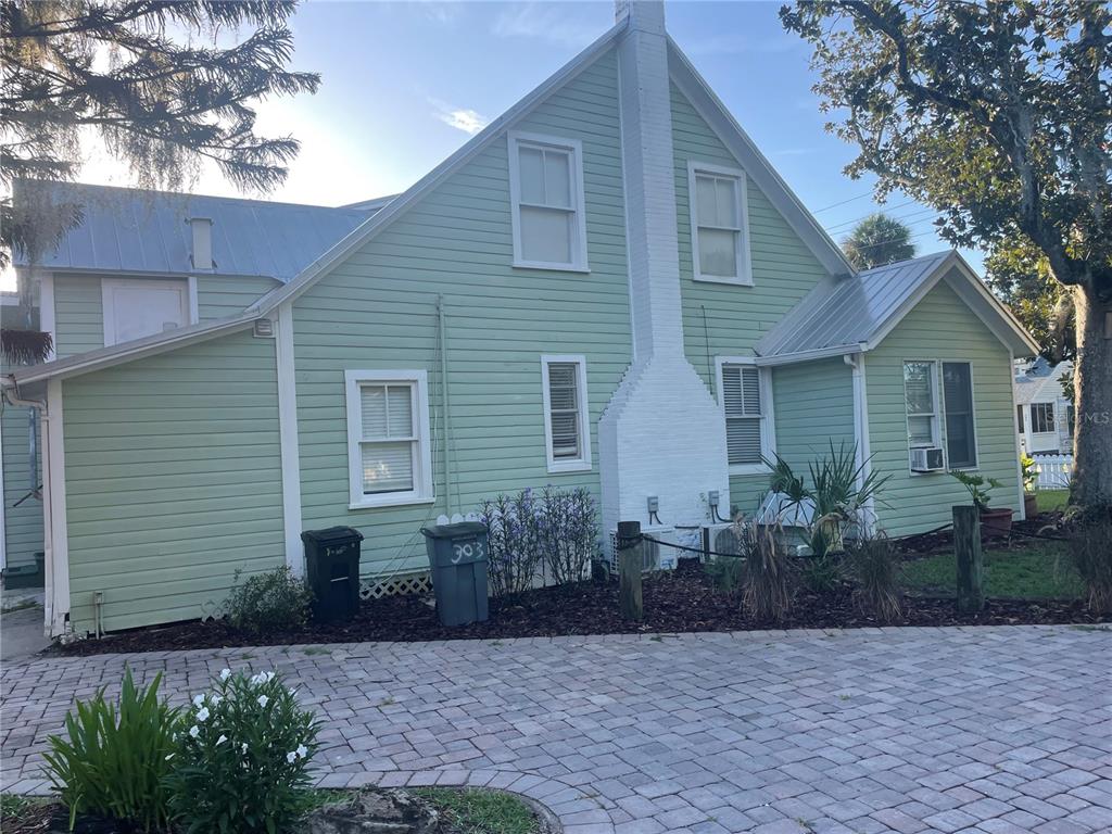 The exterior of a light green house features a white chimney and a paved driveway — 305 MARY AVENUE, NEW SMYRNA BEACH, FL