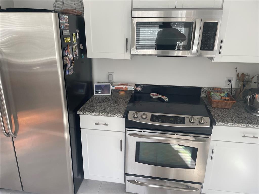 A kitchen features stainless steel appliances, white cabinets, and granite countertops — 305 MARY AVENUE, NEW SMYRNA BEACH, FL