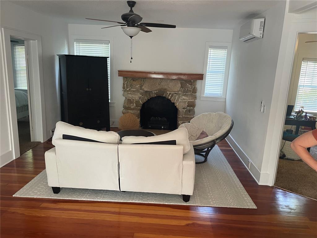 A living room features a stone fireplace, white sofa, papasan chair, and hardwood floors — 305 MARY AVENUE, NEW SMYRNA BEACH, FL