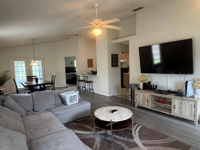 A living room features a grey sectional sofa, a round coffee table, and a wall-mounted television — 8079 GRAND PINES BOULEVARD, LAKELAND, FL