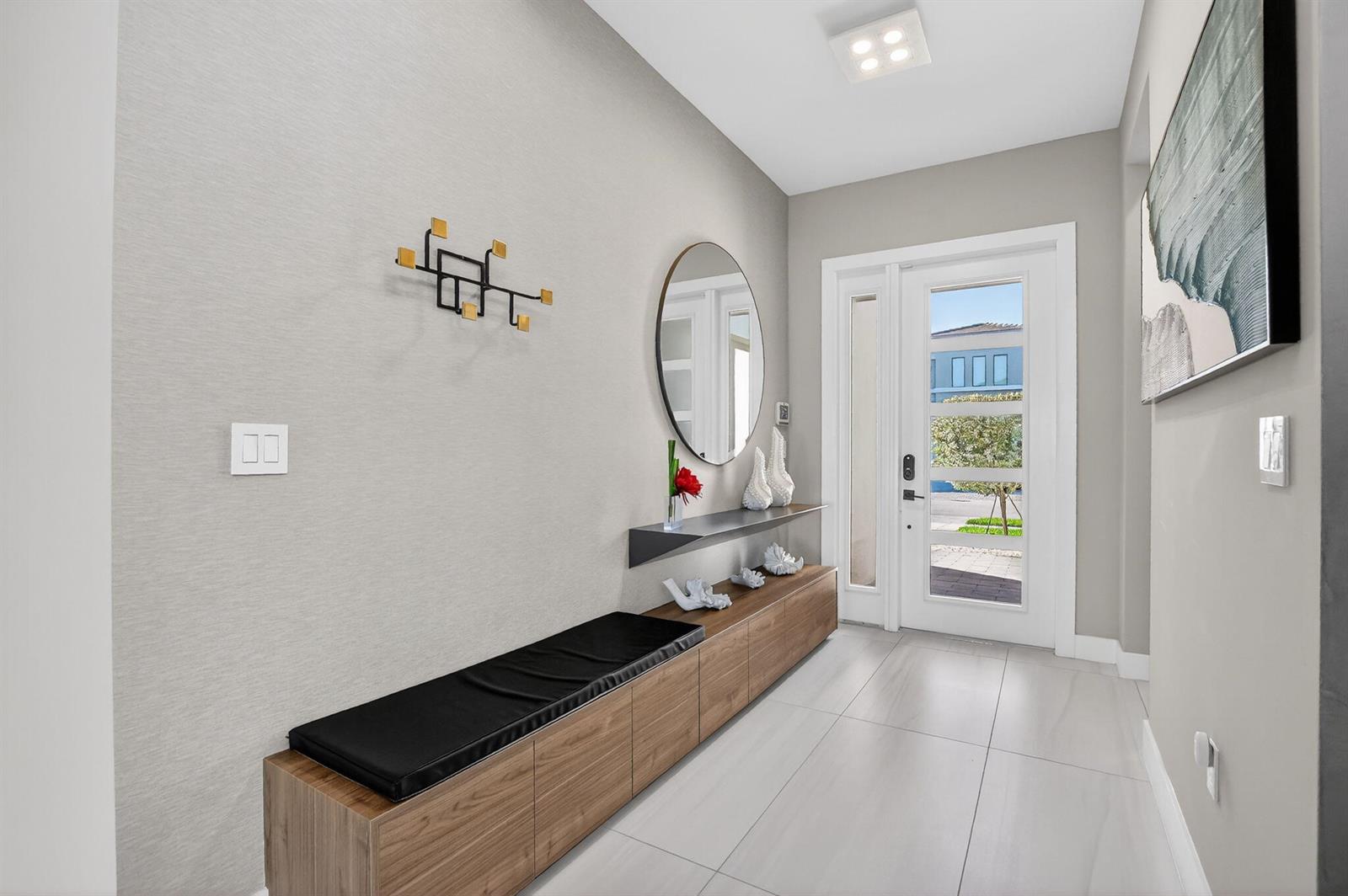 A modern entryway features a wood storage bench, a floating shelf, and a round mirror — 17080 Teton River Road, Boca Raton FL 33496, BOCA RATON, FL