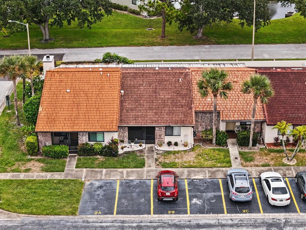 An aerial view shows a row of townhouses with tiled roofs and assigned parking spaces — 7360 ULMERTON ROAD UNIT 2B, LARGO, FL
