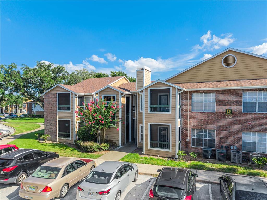 An exterior view of a two-story brick and tan siding apartment building with parking — 5530 CHRISHIRE WAY UNIT D109, ORLANDO, FL