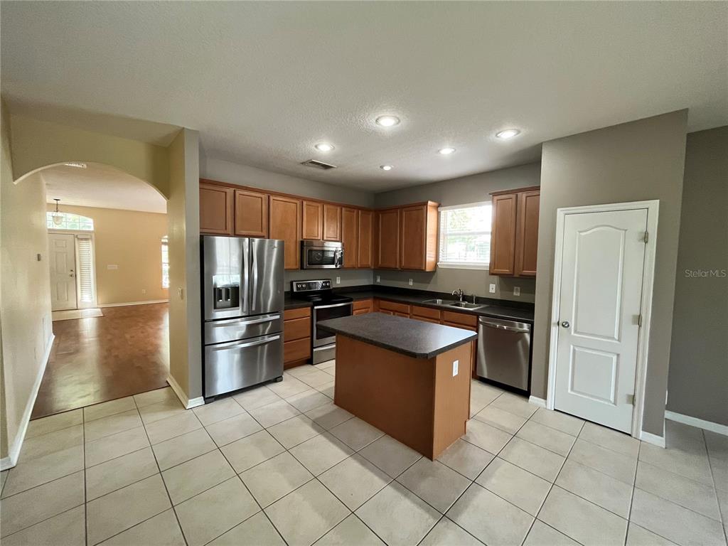 A kitchen features wood cabinets, dark countertops, stainless steel appliances, and a double sink — 919 MAGNOLIA BLOSSOM COURT, APOPKA, FL
