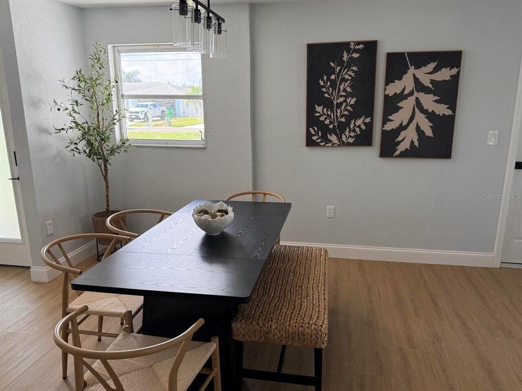 A dining room features a black table, woven chairs, a bench, and wall art — 369 WESTWINDS DRIVE, PALM HARBOR, FL